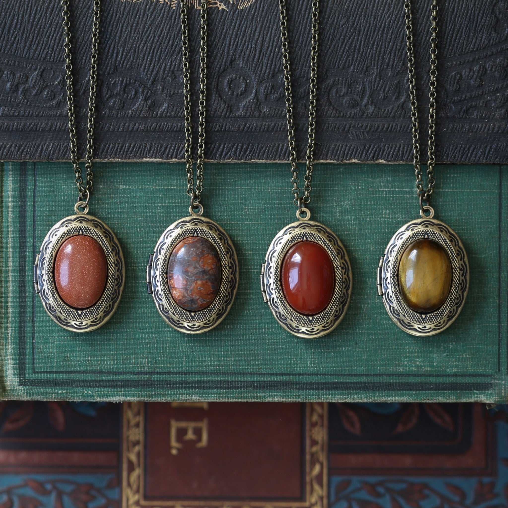 Antiqued brass vintage style long oval orange and brown semi-precious stone minerals goldstone, leopardskin jasper, tigereye, or carnelian lockets in autumn academia style great sentimental gift for student.