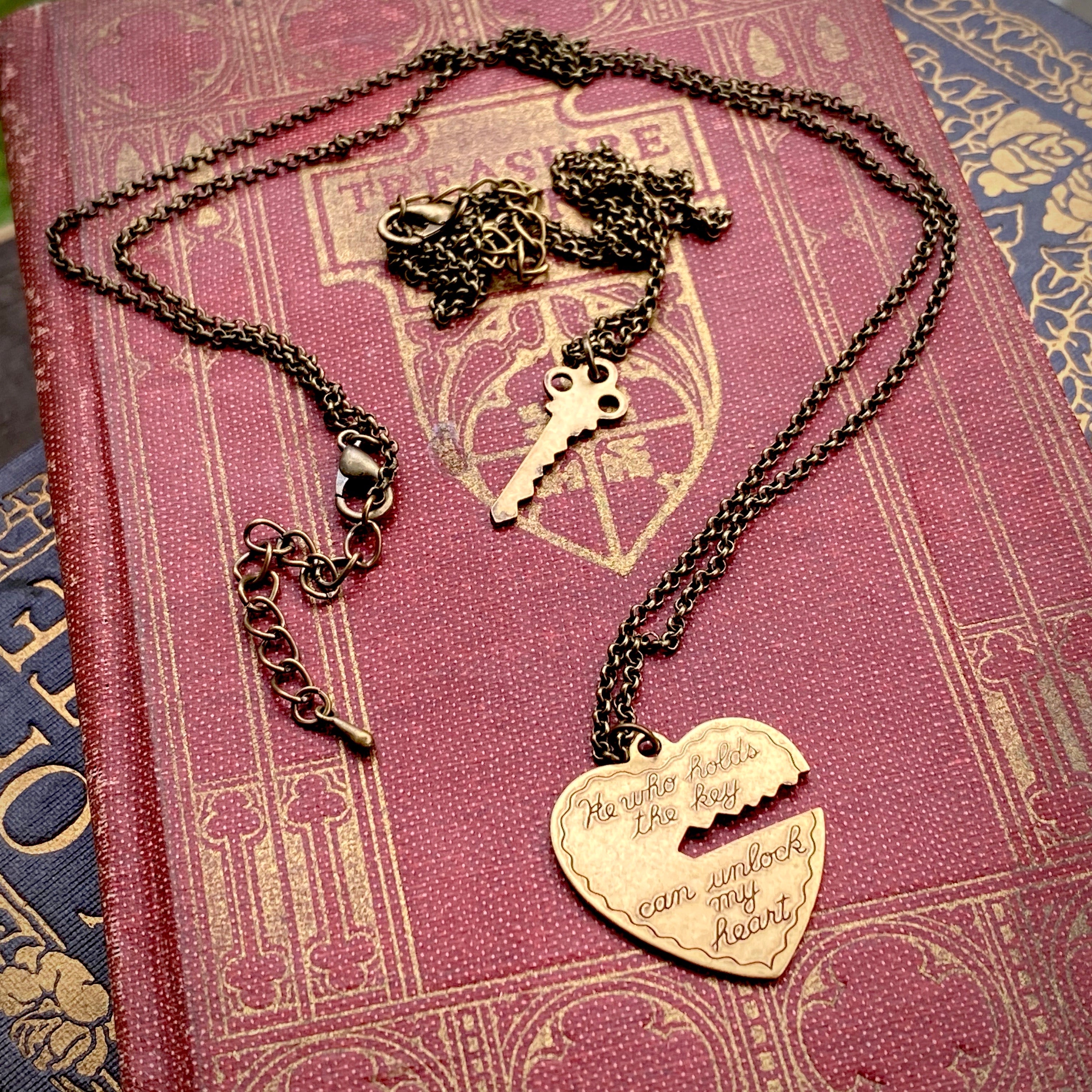 Antiqued brass necklaces. One with a key pendant and the other with a heart-shaped pendant with a key-shaped cutout.