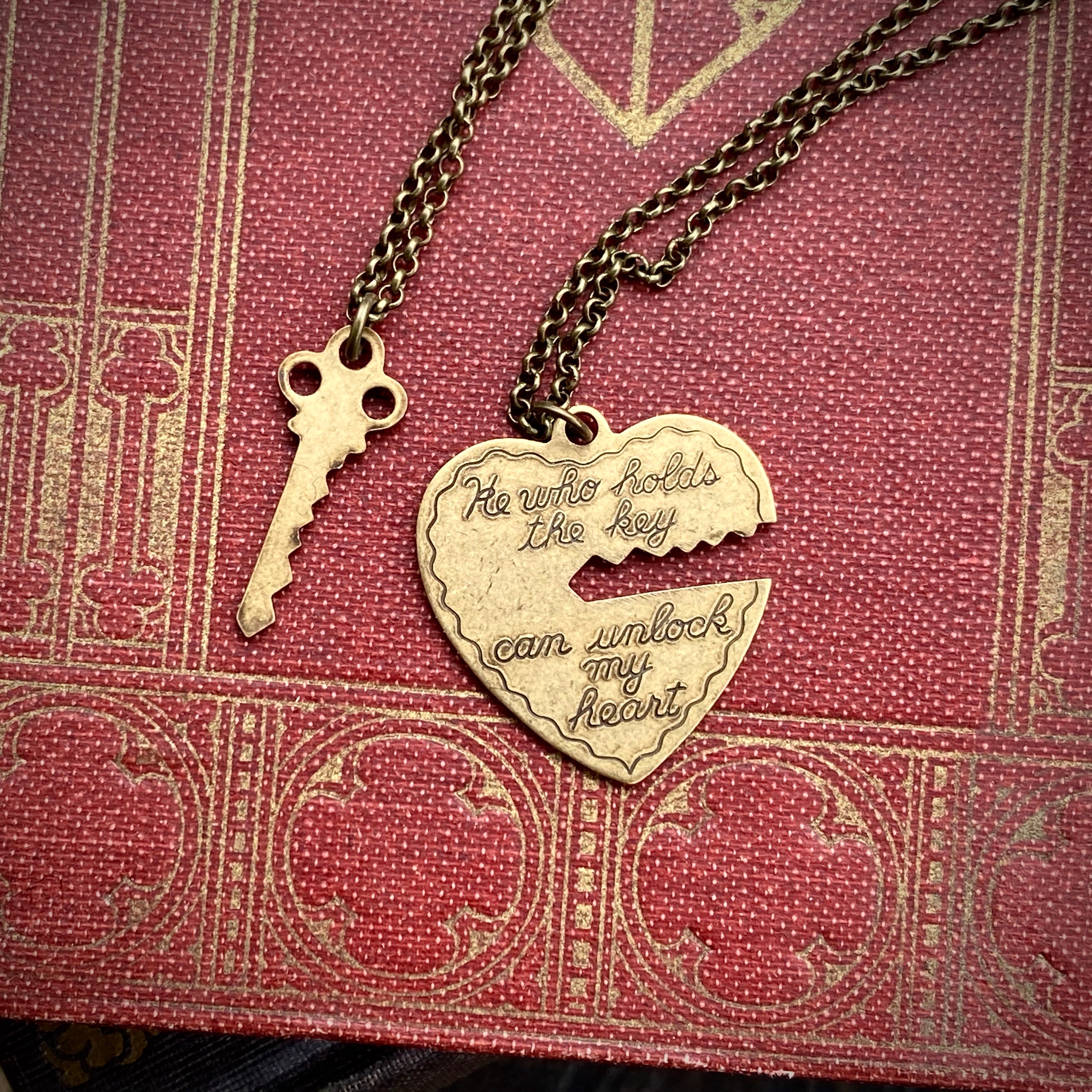 Antiqued brass necklaces. One with a key pendant and the other with a heart-shaped pendant with a key-shaped cutout.