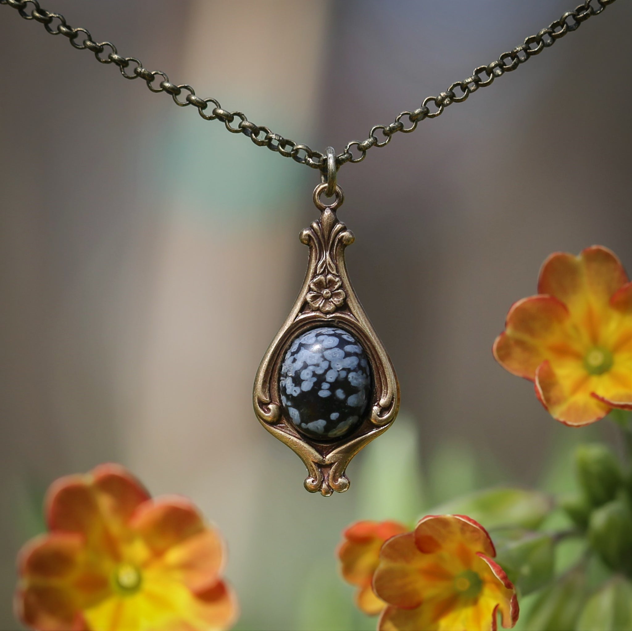 Antiqued silver vintage-inspired small romantic goth aesthetic necklace with a dainty black and gray snowflake obsidian stone on a mini floral drop setting.