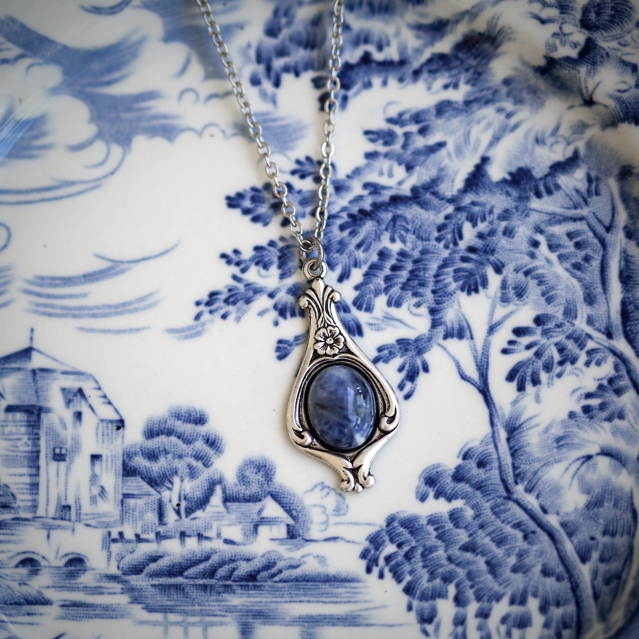 Antiqued silver vintage-inspired small fantasy astronomy aesthetic necklace with a dainty blue howlite stone on a mini floral drop setting.