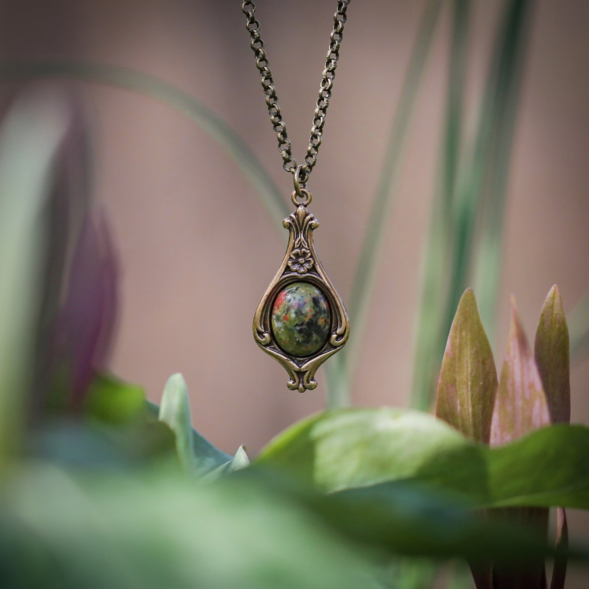 Antiqued brass vintage inspired small mosscore aesthetic necklace with a dainty green unakite stone on a mini floral drop setting.