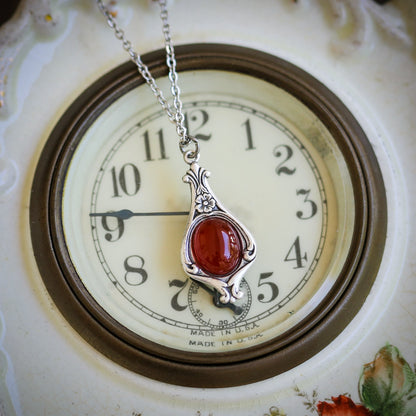 Antiqued silver vintage-inspired small tomato girl aesthetic necklace with a dainty orange carnelian stone on a mini floral drop setting.