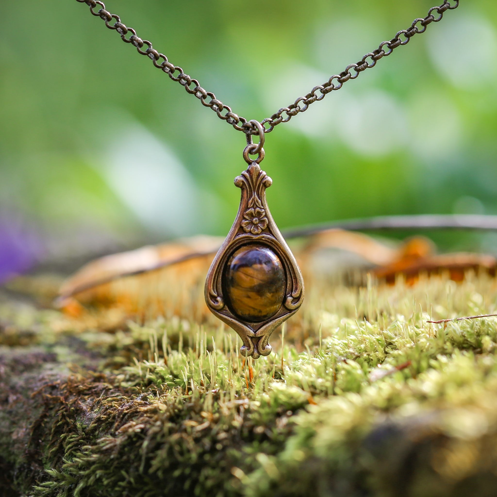 Antiqued brass vintage inspired small goblin academia aesthetic necklace with a dainty brown tiger eye stone on a mini floral drop setting.