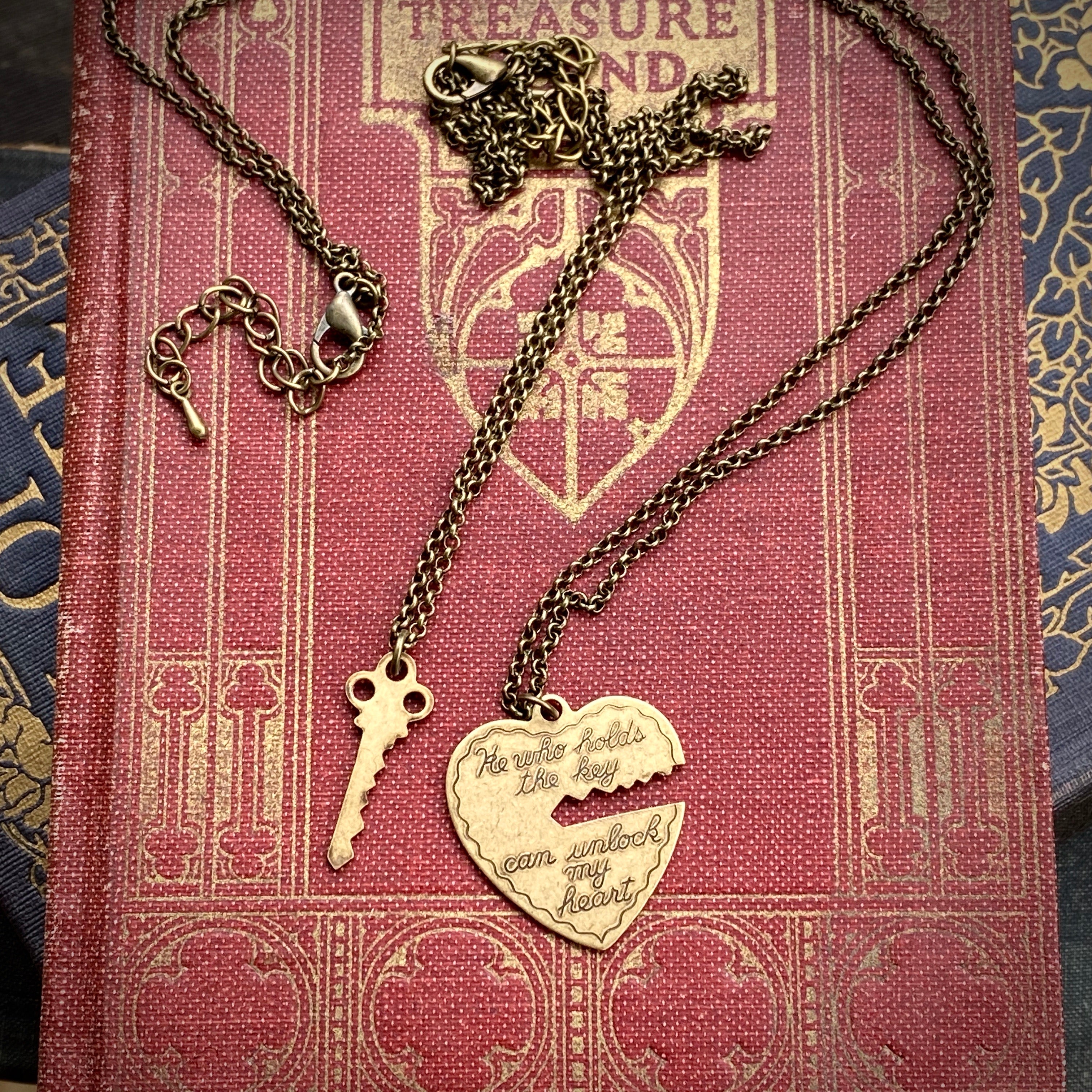 Antiqued brass necklaces. One with a key pendant and the other with a heart-shaped pendant with a key-shaped cutout.