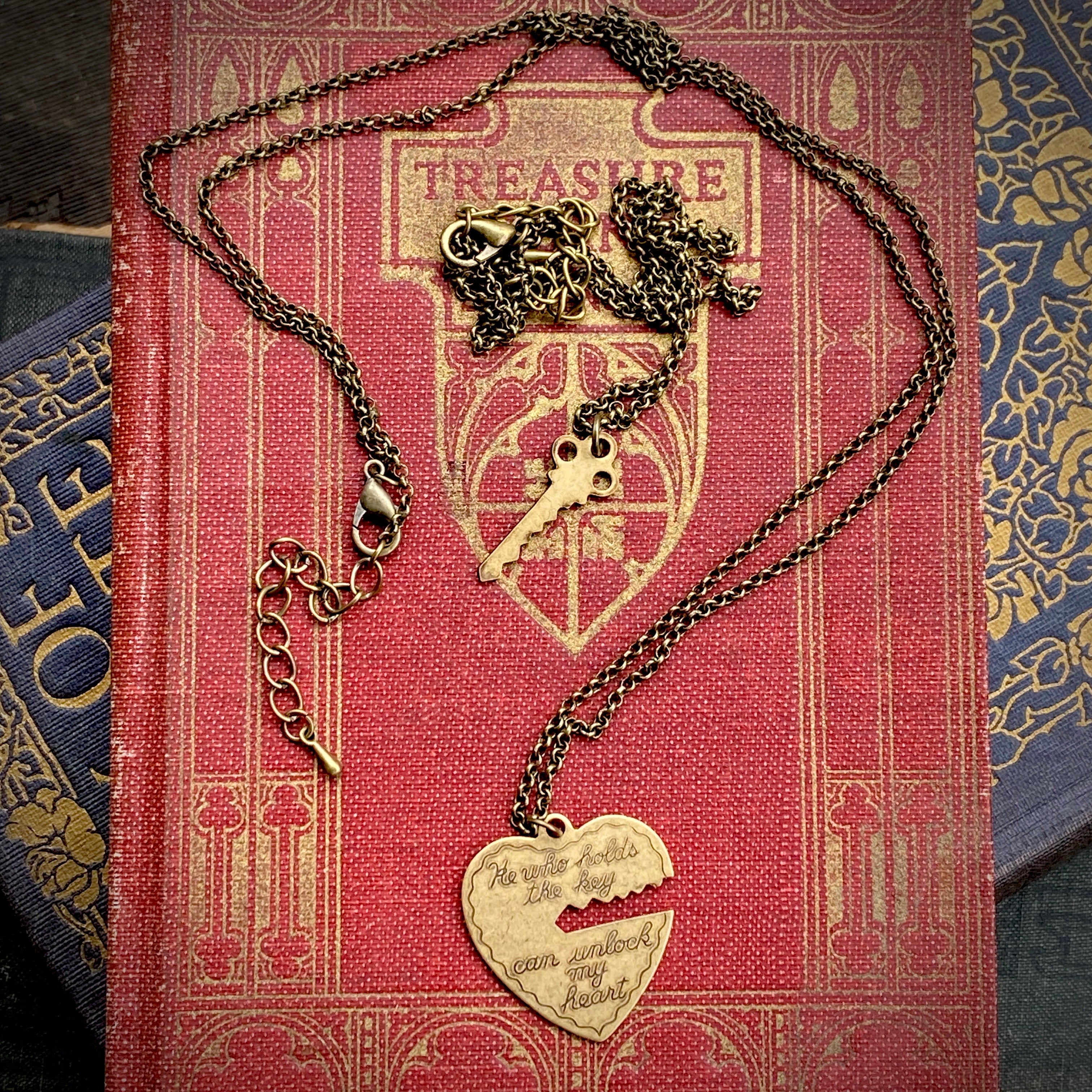 Antiqued brass necklaces. One with a key pendant and the other with a heart-shaped pendant with a key-shaped cutout.