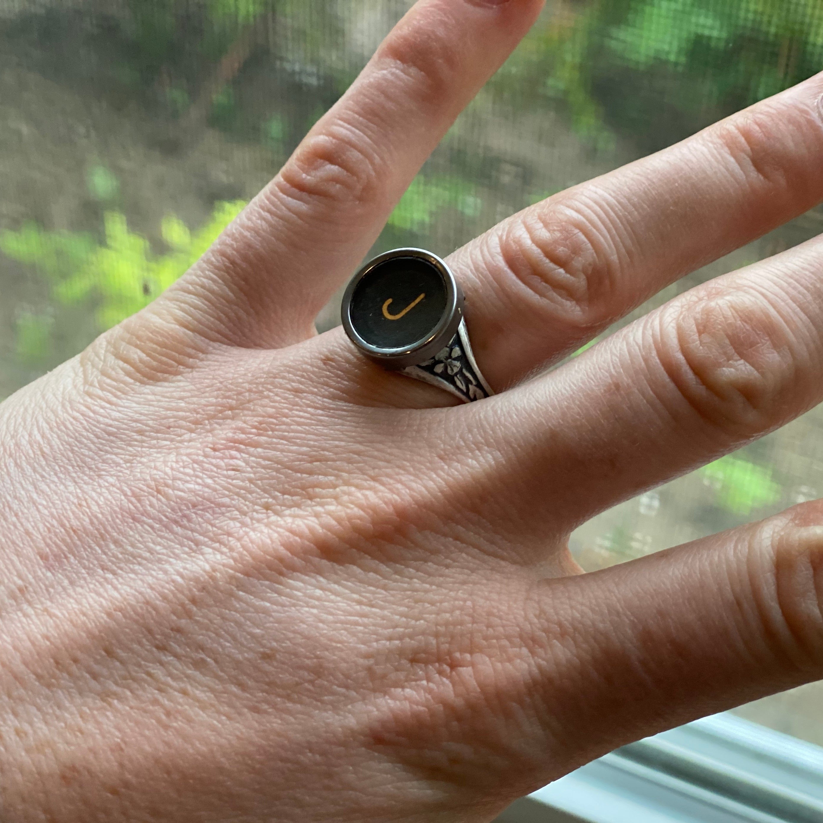 Silver adjustable ring with an authentic vintage typewriter key as the centerpiece. The key is metal-rimmed with glass covering an off-white letter 'J' on a black background.