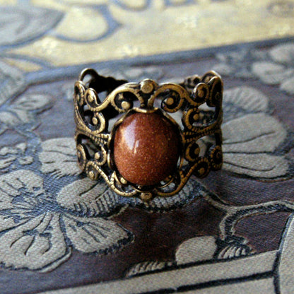 Antiqued brass modern vintage inspired adjustable filigree ring set with an orange goldstone semi-precious mineral in the autumn academia aesthetic