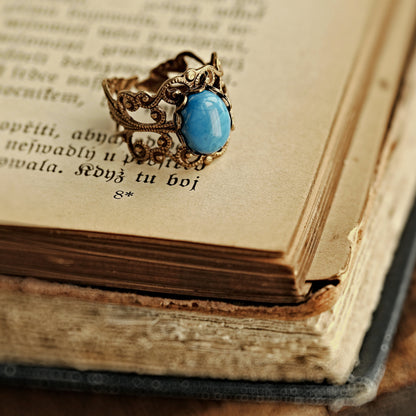 antiqued brass modern vintage inspired adjustable filigree cocktail ring with a turquoise blue howlite oval semi-precious mineral stone in the boho fashion aesthetic.